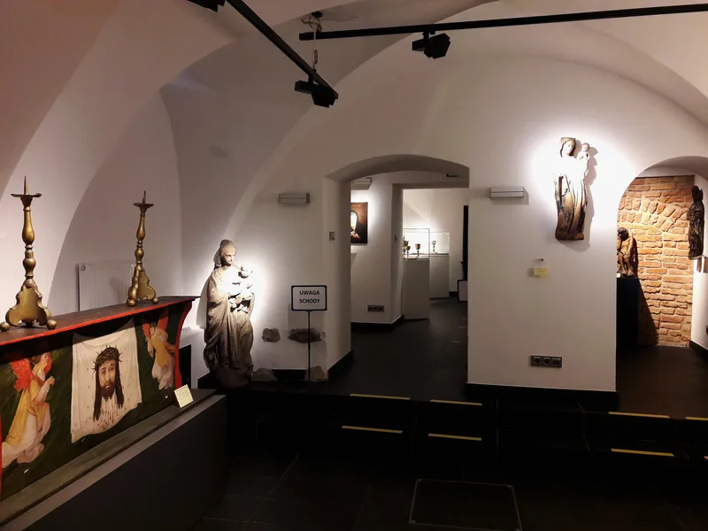 Sklepiona sala z gotyckimi rzeźbami sakralnymi i lichtarzami w Muzeum Archidiecezji Warszawskiej