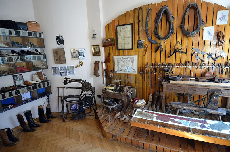 Warsztat szewski z XIX wieku z oryginalną maszyną do szycia, kopytami i wystawą butów