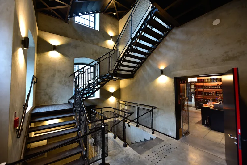 Industrial staircase inside the Polish Vodka Museum, with metal stairs and the bare plastered walls of the former rectification building