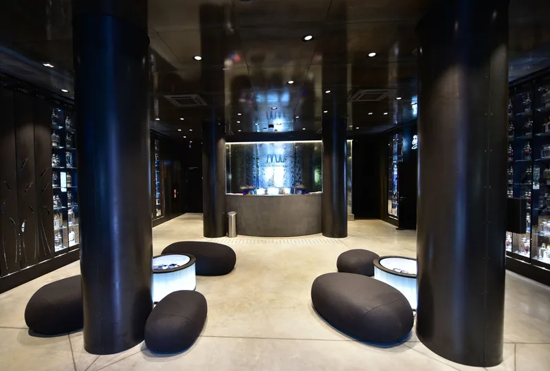 Lobby of the Polish Vodka Museum with dark columns, seating, and illuminated bottle displays in the background