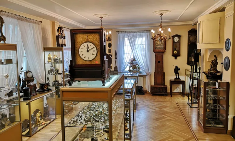 Sala wystawowa z zegarami stojącymi i gablotami z narzędziami zegarmistrzowskimi