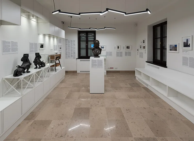 Wnętrze sali wystawy stałej „Gabinet Wolski” w Muzeum Woli, gabloty i fotografie na ścianach