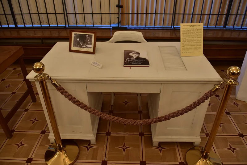 Biurko i fotel Marii Skłodowskiej-Curie za sznurem odgradzającym, z portretem i egzemplarzem autobiografii