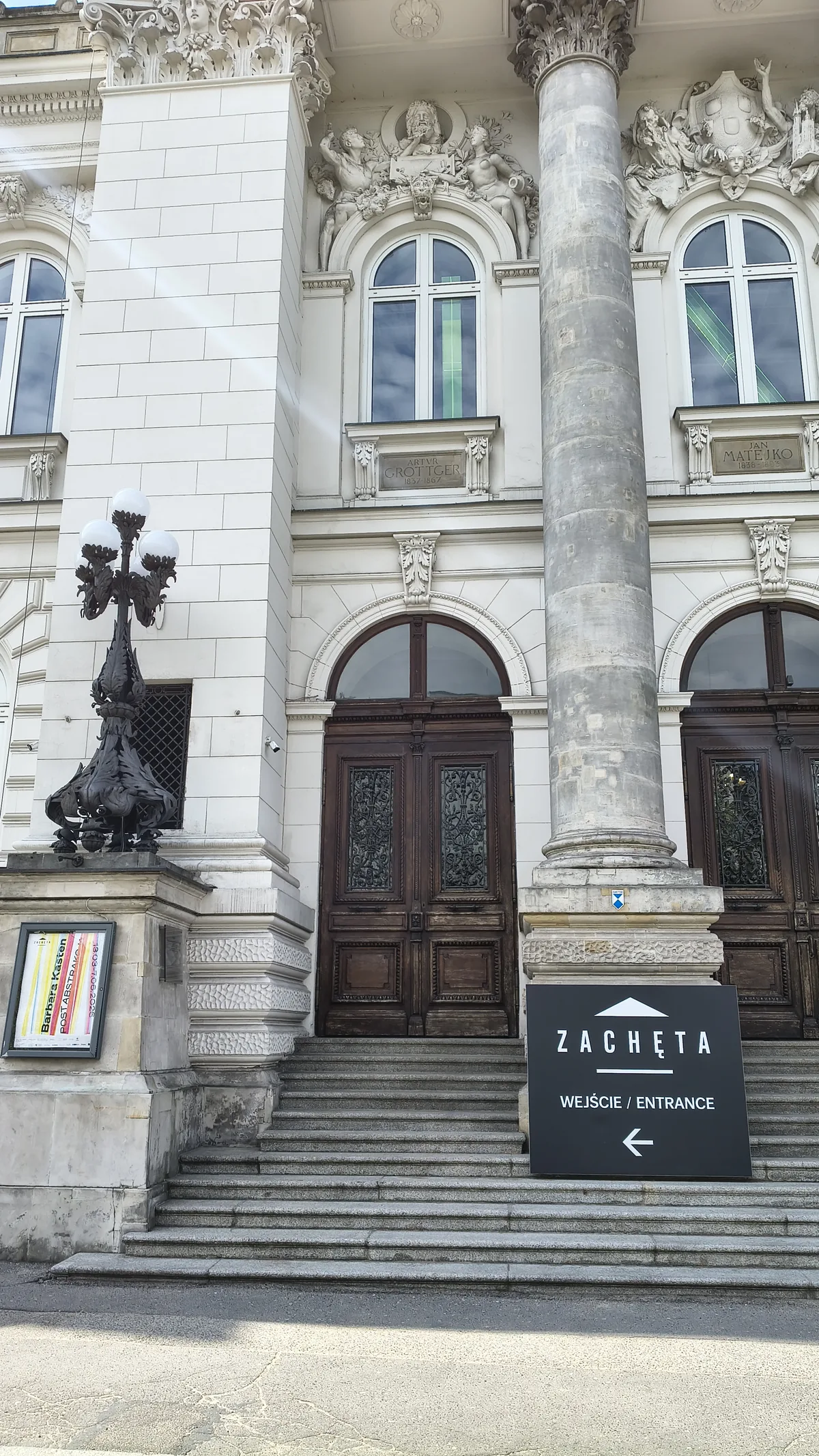 Zacheta main entrance - heavy wooden doors, column, sign reading ZACHĘTA WEJŚCIE/ENTRANCE