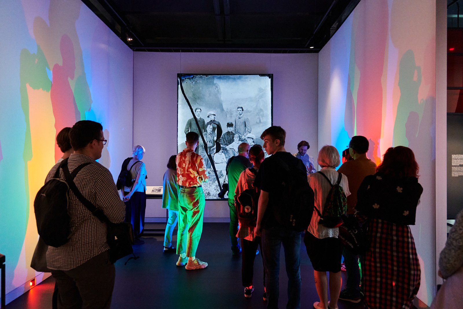 A group of visitors before a large historical photograph in a colour-lit room of the Museum of Photography in Krakow, Rakowicka street