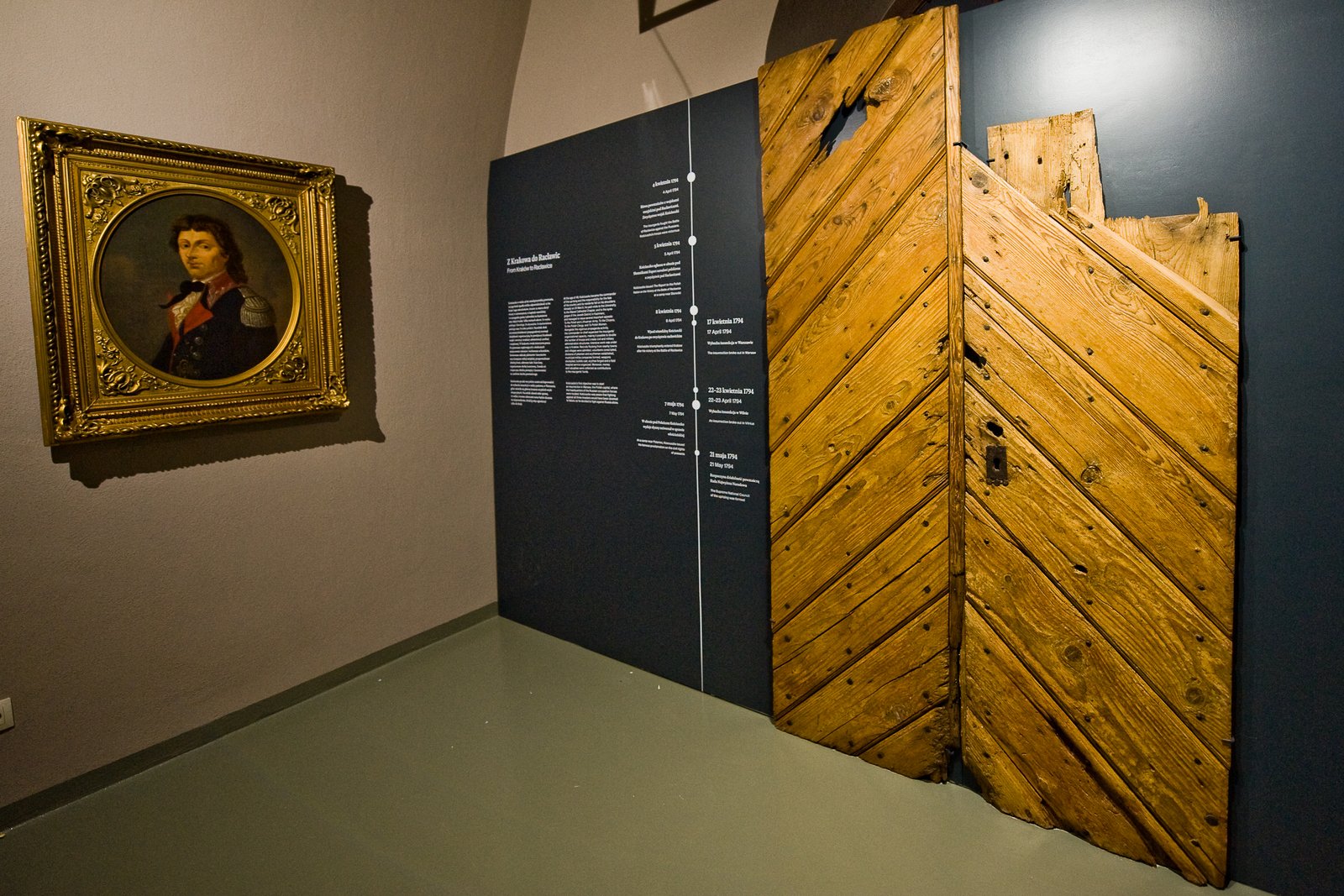 A portrait of Tadeusz Kościuszko in a gilded frame and an old wooden door in the Kościuszko Museum exhibition in Krakow