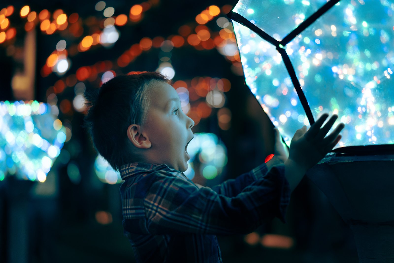 A boy reaching out to a glowing light installation at the WOMAI Science and Senses Centre in Krakow