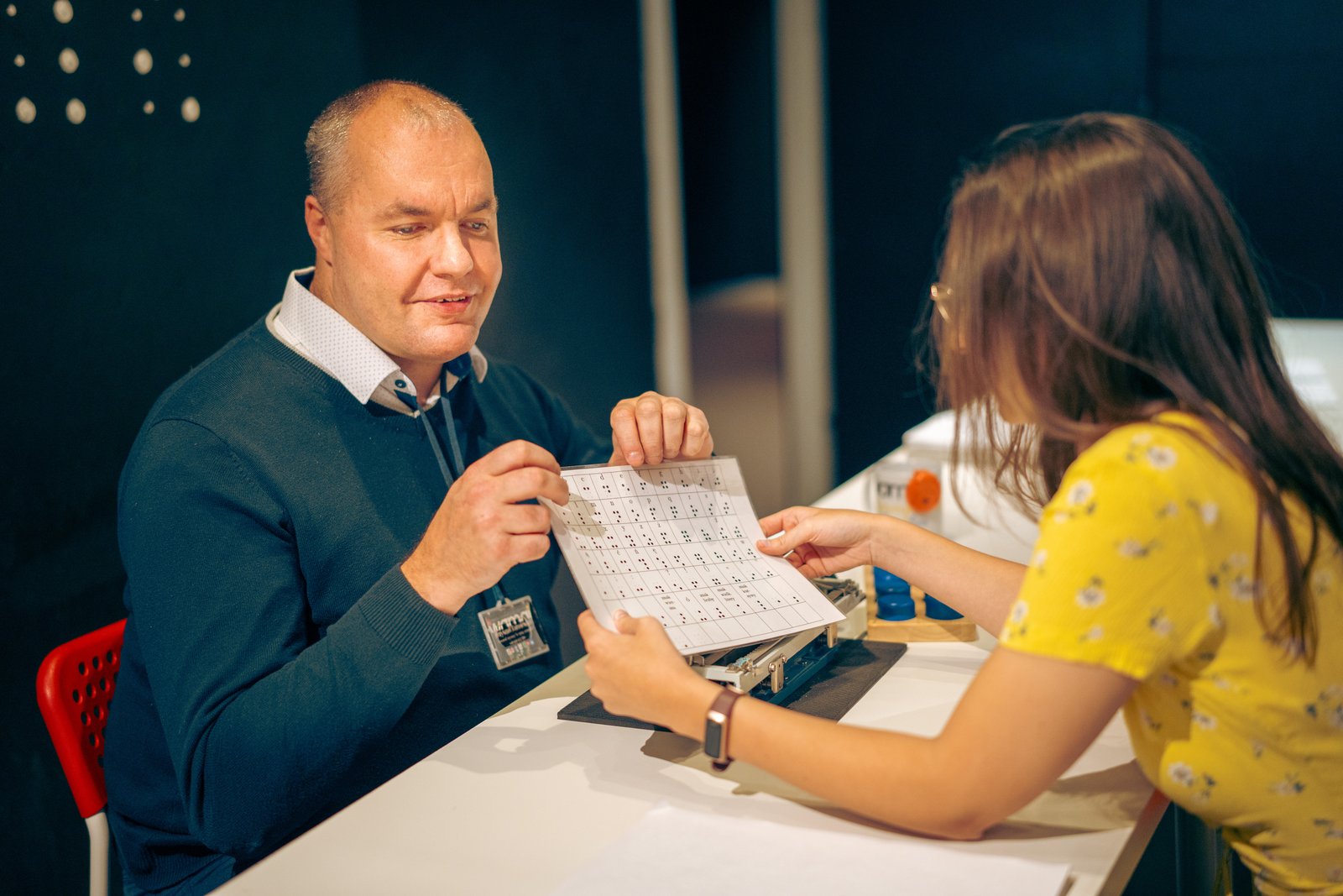 A guide showing a visitor a Braille card at the WOMAI Science and Senses Centre in Krakow